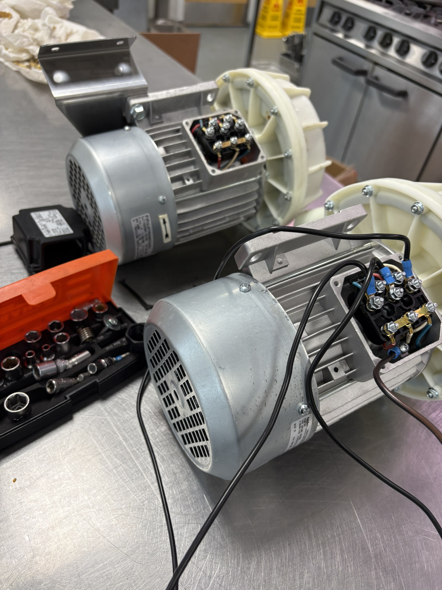 Two grey centrifugal blower motors prepared for component replacement