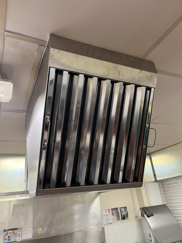 Clean stainless-steel baffle filters fitted to a commercial kitchen extract canopy